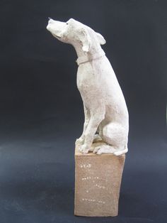 a white dog statue sitting on top of a block