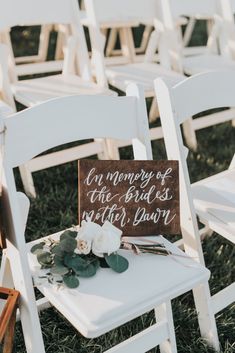 a sign that says ceremony of the bride and groom on a white chair with flowers