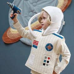 a young boy dressed as a spaceman holding a blow dryer in his hand