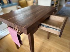 a close up of a wooden table with a drawer on it's side and a pink cloth under the edge