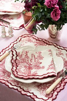 red and white place setting with pink flowers in vase on tableclothed table cloth