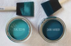 two paint cans with teal ocean and dark harbor written on them next to each other