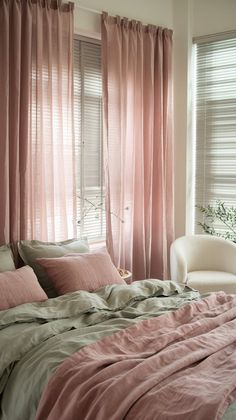 a bed with pink sheets and pillows next to a window covered in sheer drapes