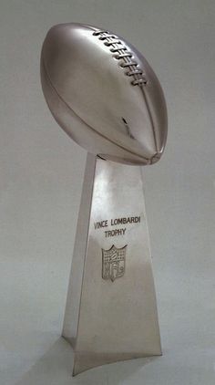 a silver football trophy sitting on top of a white table