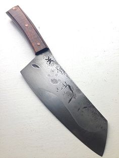 a large knife with a wooden handle on a white surface and the blade has been cut off