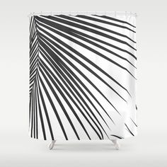 a shower curtain with black and white palm leaves on the outside, in front of a gray background