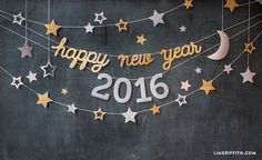 a happy new year banner with stars and moon hanging from it's sides on a chalkboard wall