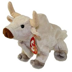 a white stuffed cow with horns and a tag on it's ear is laying down