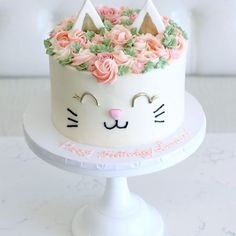 a white cake decorated with pink roses and cat ears