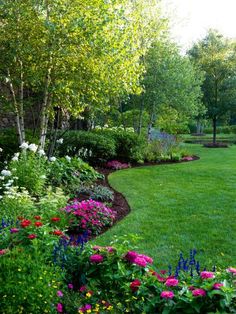 a lush green lawn surrounded by flowers and trees