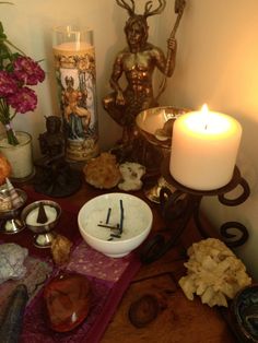 a table topped with lots of different types of items next to a candle and vase