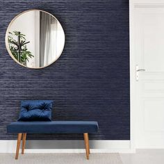 a blue bench sitting in front of a round mirror on the side of a wall