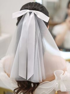 the back of a bride's head wearing a veil with white ribbon on it