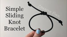 a hand holding a black cord with the words simple sliding knot bracelet written on it