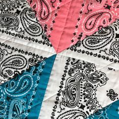 a close up of a quilt with different colors and patterns on it, including pink, blue, and black