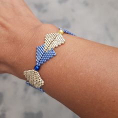 a woman's arm wearing a bracelet with blue beads and gold clasps on it