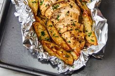 chicken and potatoes in foil on a baking sheet with seasoning sprinkles