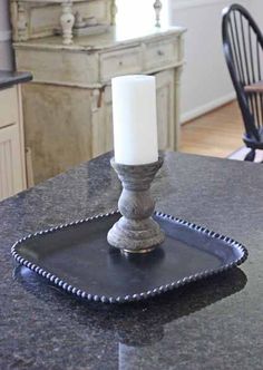 a candle is sitting on top of a black tray in the middle of a kitchen