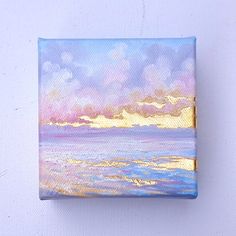 a painting on a glass block with water and clouds in the background at sunset or sunrise