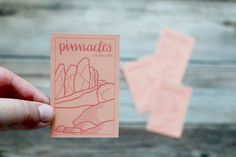 a hand holding up a piece of pink paper with the words pinnacles on it