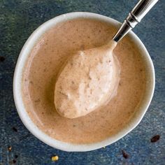 a spoon in a small bowl filled with some kind of sauce on top of a table