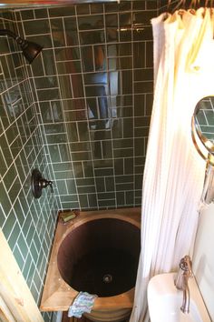 a small bathroom with green tile and a brown bathtub in the corner, next to a white sink