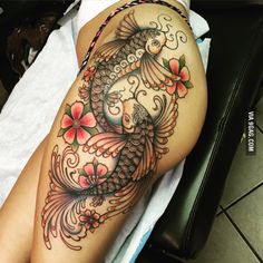 a woman's leg with a fish tattoo on it and flowers around the legs