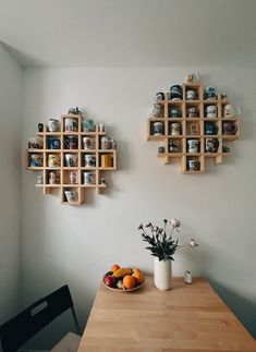 two wooden shelves on the wall above a table with fruit and flowers in vases