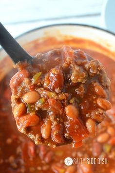 a spoon full of chili and beans in a pot