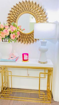 a white table topped with pink flowers next to a mirror and vase filled with roses