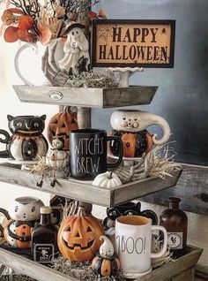 a three tiered tray filled with coffee mugs and halloween decorations