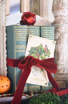 a stack of books tied with a red ribbon next to an orange and other christmas decorations