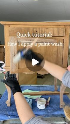 a woman is painting a piece of furniture with white paint and black gloves on her hands