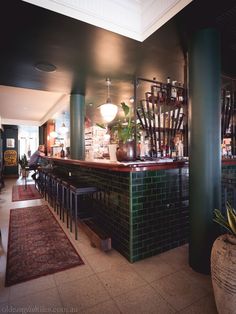 a bar with lots of bottles on the counter and plants in vases behind it