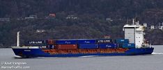 a large blue and white cargo ship sailing in the water with mountains in the background