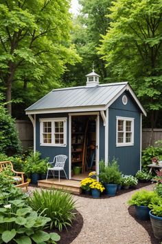 a small blue shed surrounded by trees and flowers