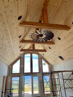 a large open room with wooden walls and ceiling fan in the center, overlooking mountains