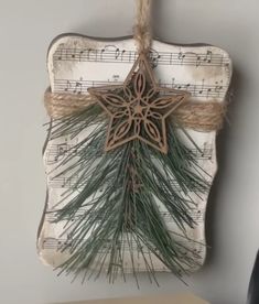 a wooden star hanging on a wall with music notes and pine needles attached to it