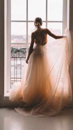 a woman standing in front of a window wearing a dress