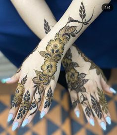 a woman's hands with henna tattoos on her arm and hand, both decorated with gold flowers