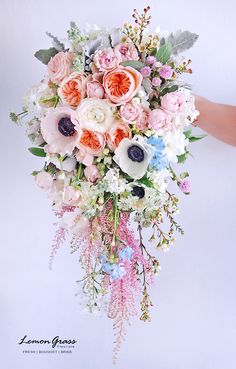 a bouquet of flowers is being held by someone's hand on a white background