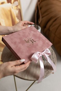 a person holding a pink box with a ribbon around it