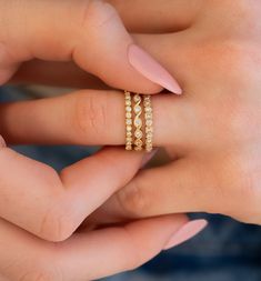 a woman's hand with two gold rings on her left and the other hand holding an engagement ring