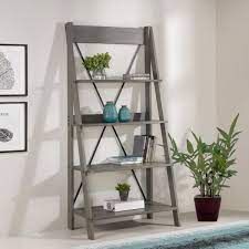 a shelf with books, plants and pictures on the wall behind it in a living room