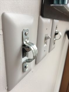 two white switch plates mounted to the side of a wall next to a door handle