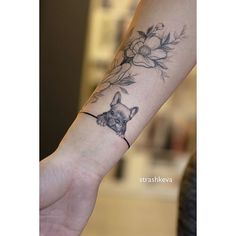 a woman's arm with a tattoo on it that has flowers and a cat