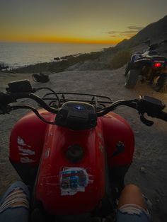 two motorcycles parked on the beach at sunset