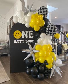 balloons and decorations are arranged in the shape of a smiley face on top of a sign that says one happy dude