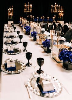 a long table is set up with blue flowers and candles for an elegant dinner party