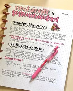 an open notebook with spanish words and a pink pen